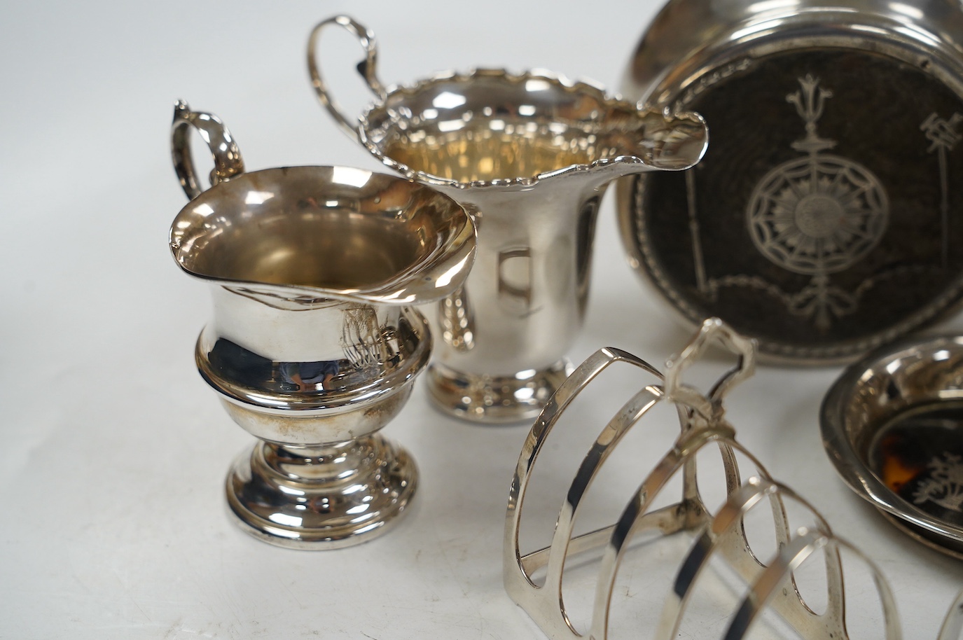 Sundry small silver including a pair of toast racks, Sheffield, 1936, three cream jugs, a sauceboat and two tortoiseshell mounted items. Condition - poor to fair to good